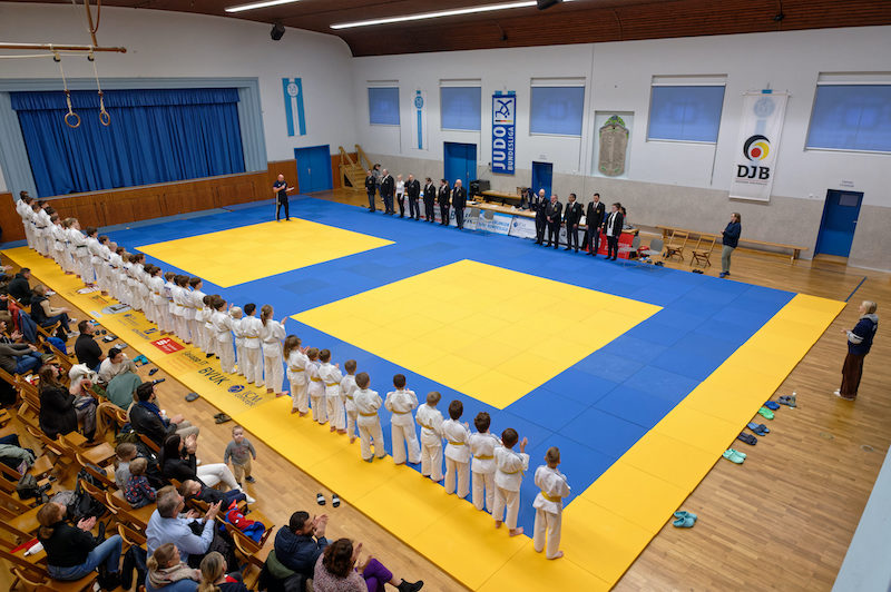 Das Bild zeigt die Aufstellung der Erlanger Jugend bei den Stadtmeisterschaften 2022. Im Hintergrund hängen die Fahnen des DJB und der Bundesliga Judo
